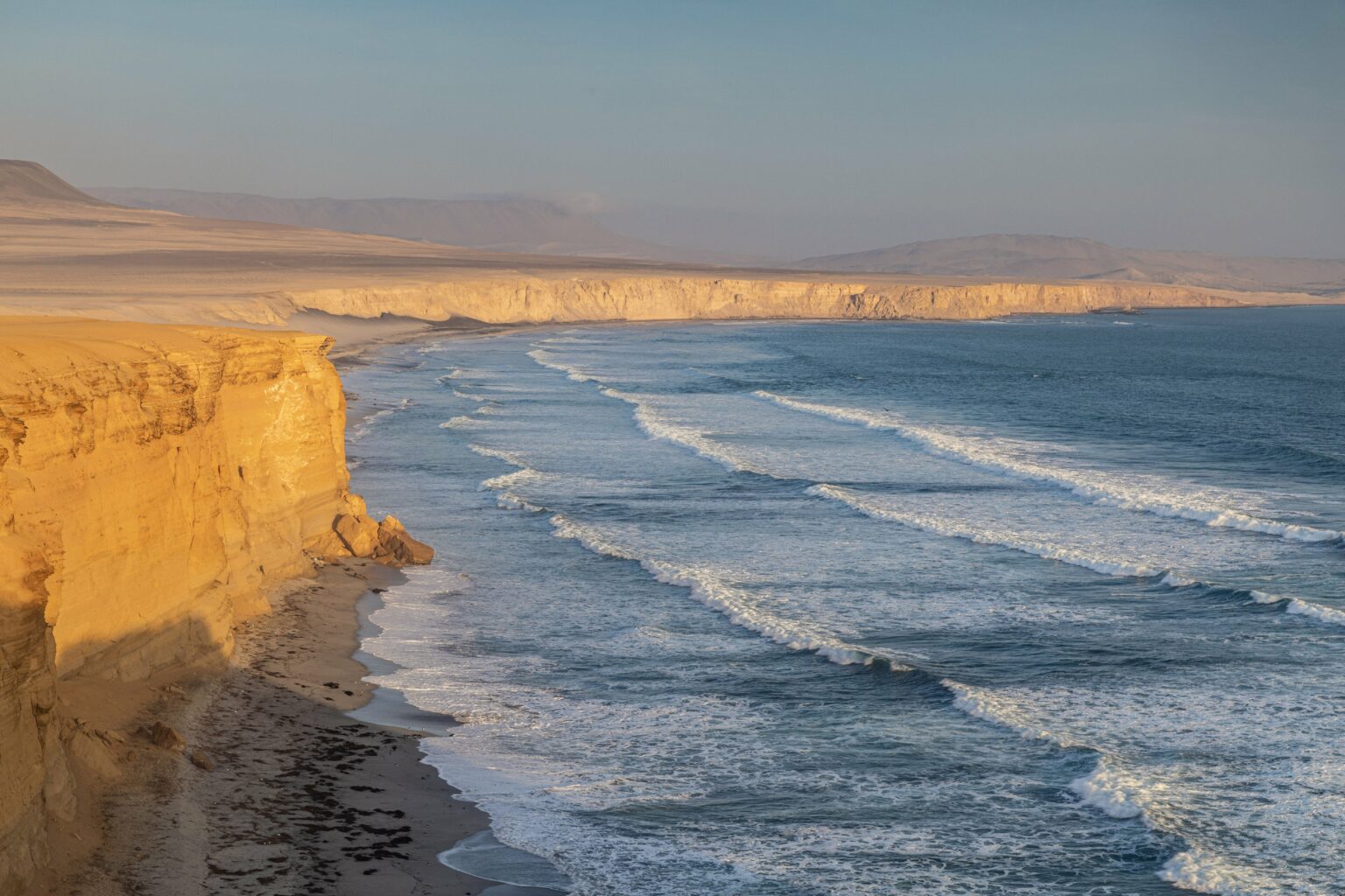 Acantilados dorados del desierto costero junto al océano Pacífico en la Reserva Nacional de Paracas, Perú